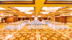 A spacious banquet hall at Pride Plaza Ahmedabad, featuring a large number of tables arranged in rows, ready for a conference or event.